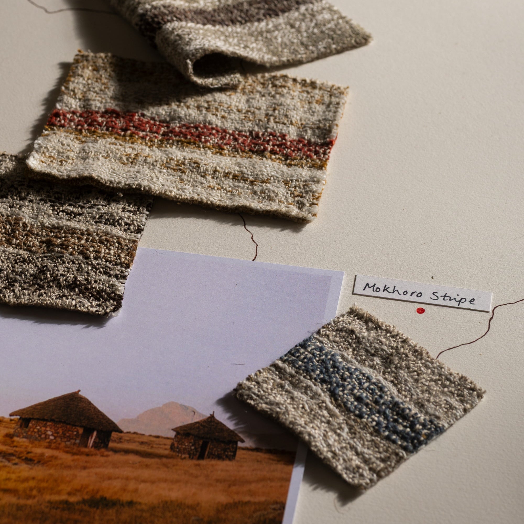 Textured fabric swatches on a surface with a landscape photo and label.