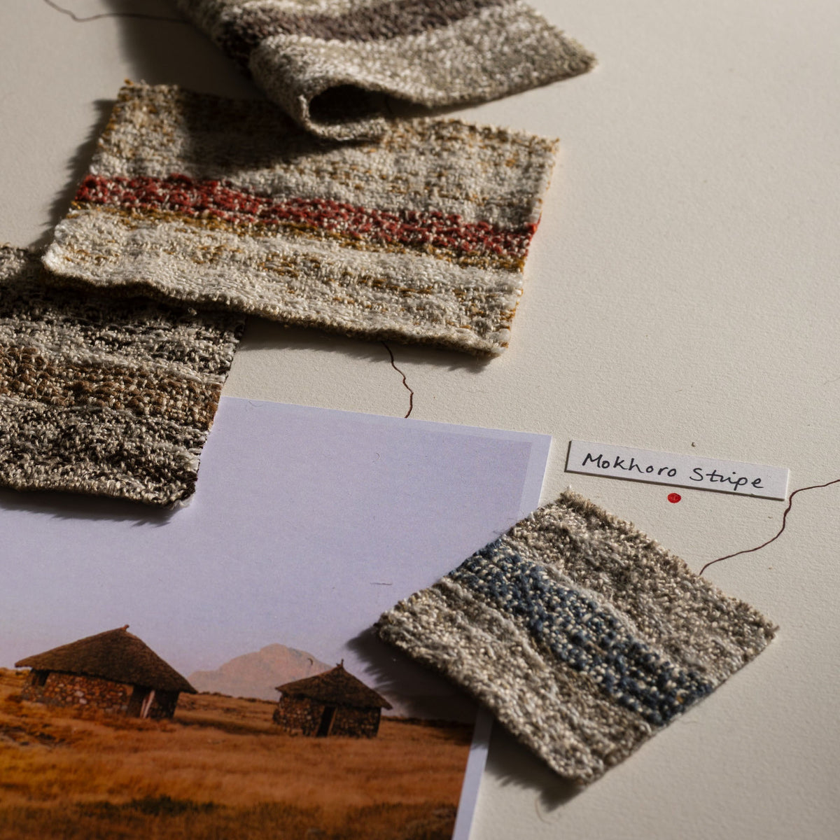 Textured fabric swatches on a surface with a landscape photo and label.