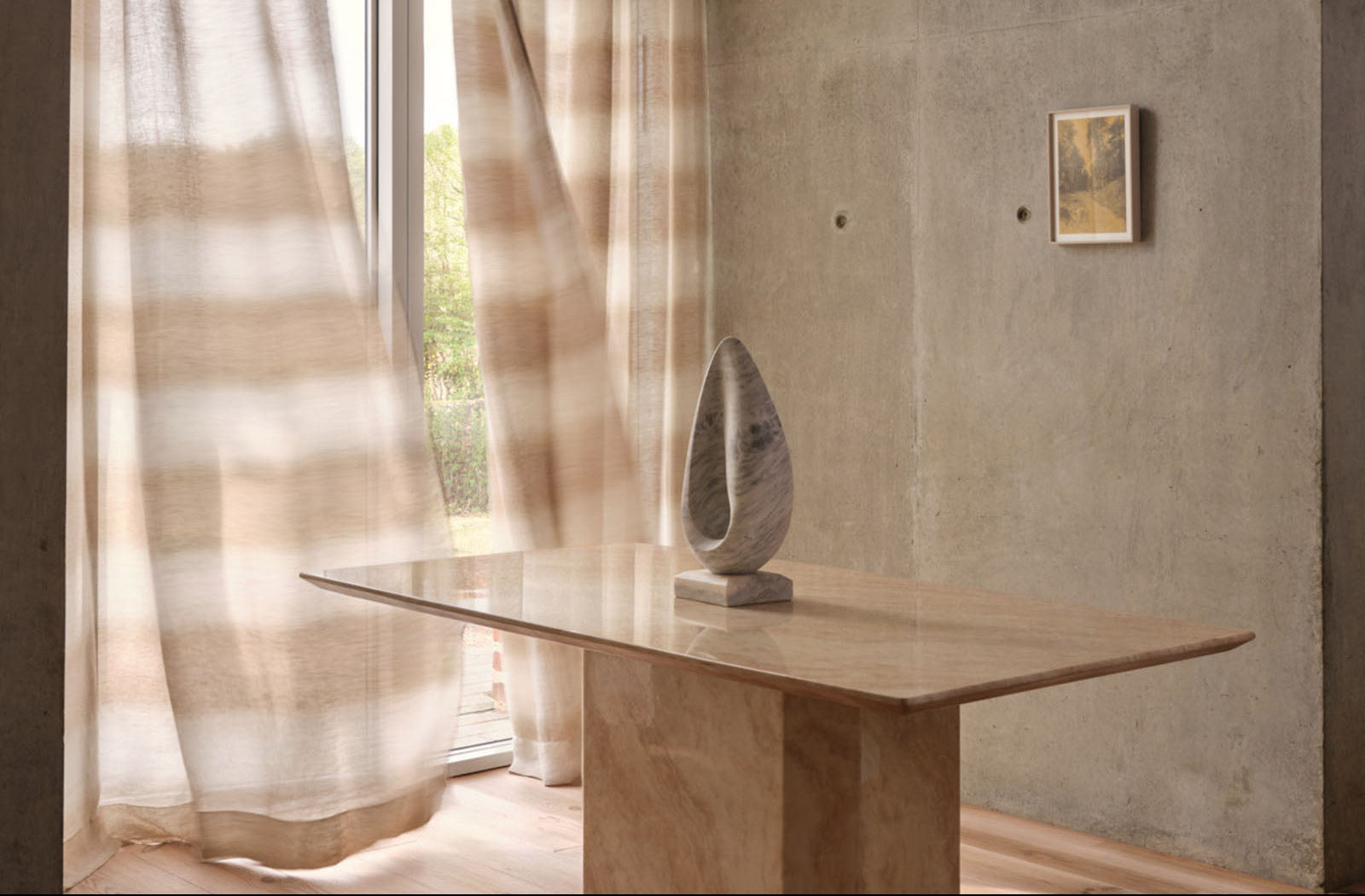 Modern interior with a stone table and sculpture, soft lighting, and neutral tones.