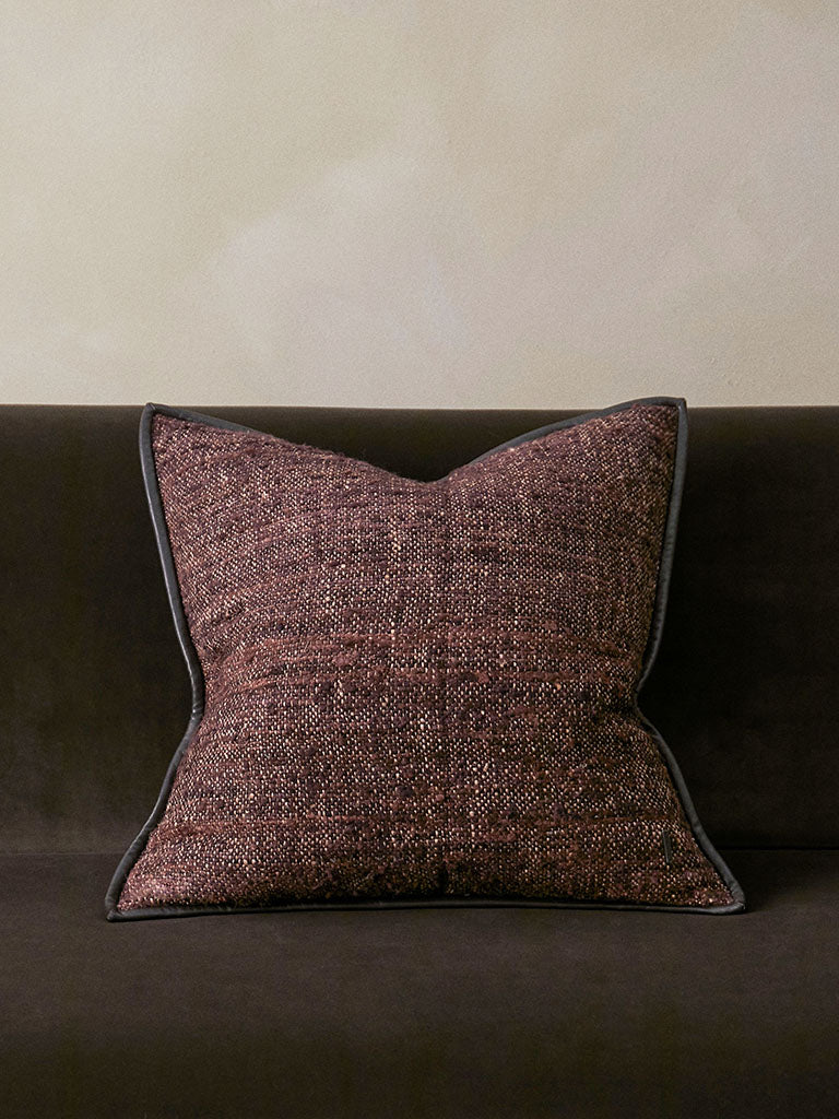 Textured brown pillow on a dark brown sofa against a beige wall