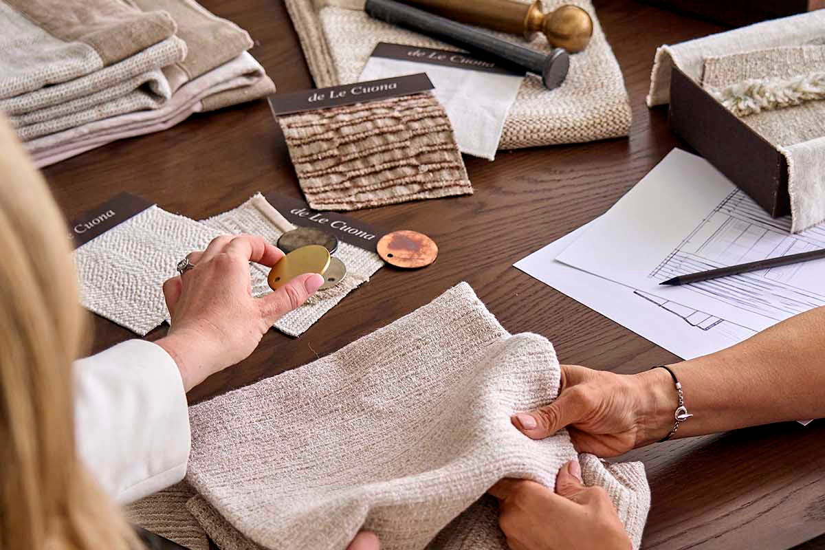 Two people examining fabric swatches on a table with design documents.