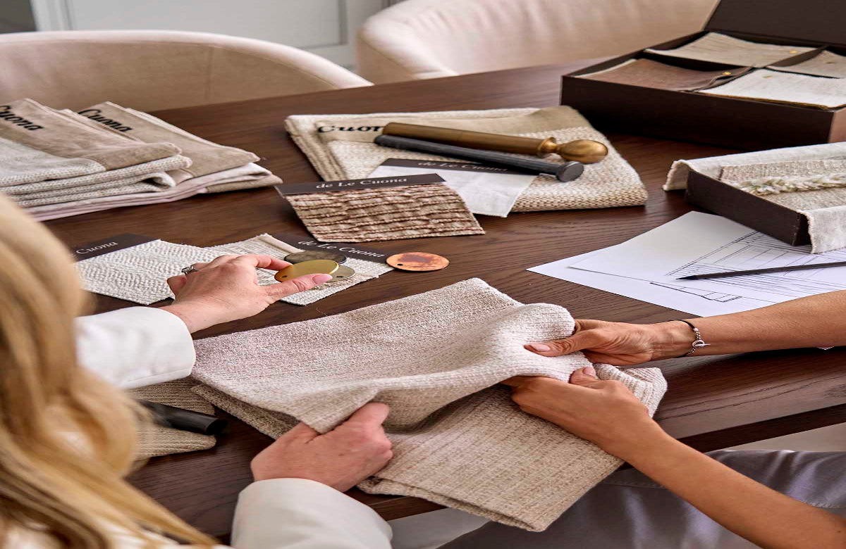 Two people examining fabric swatches on a table with design documents.