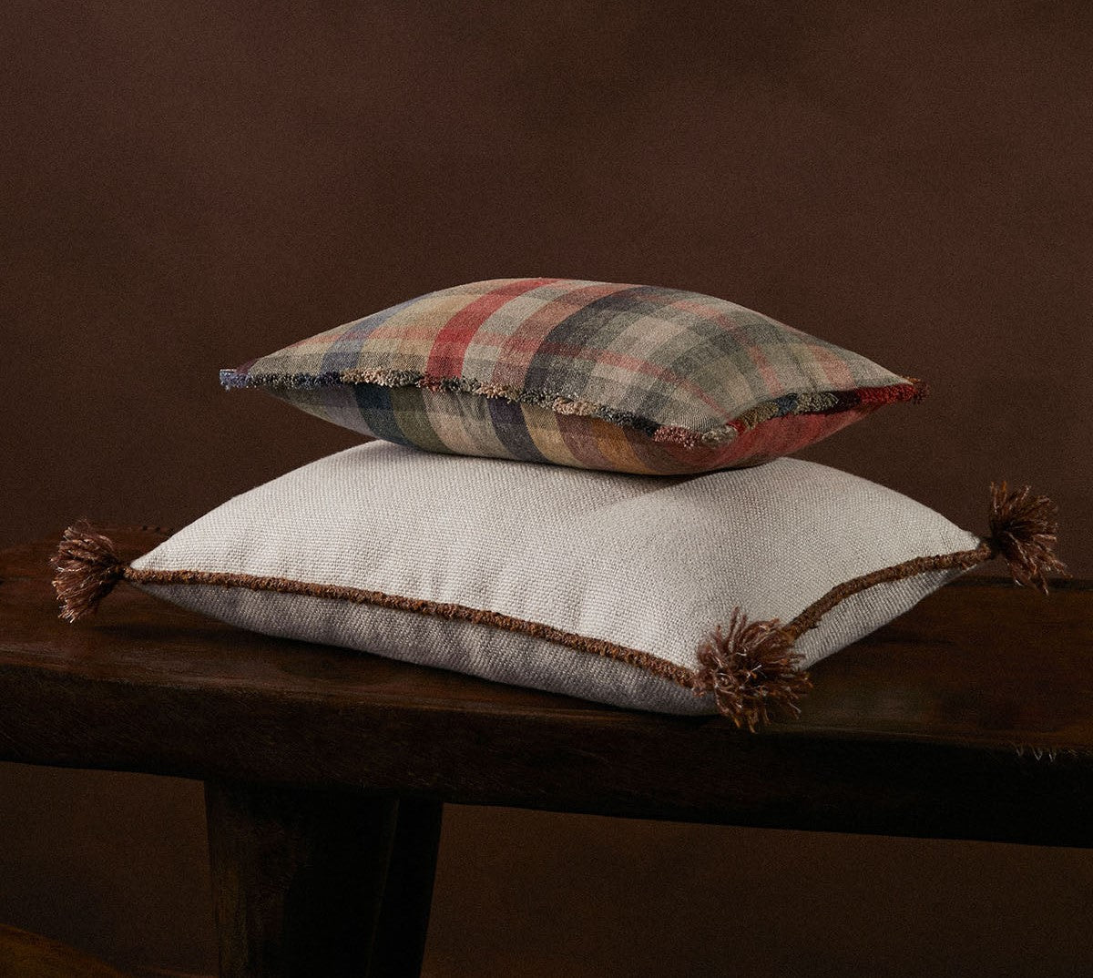 Two textured pillows stacked on a wooden surface with a dark background
